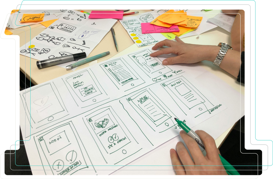 Picture of a table and a persons while working on sketches of website wireframes and post-it notes